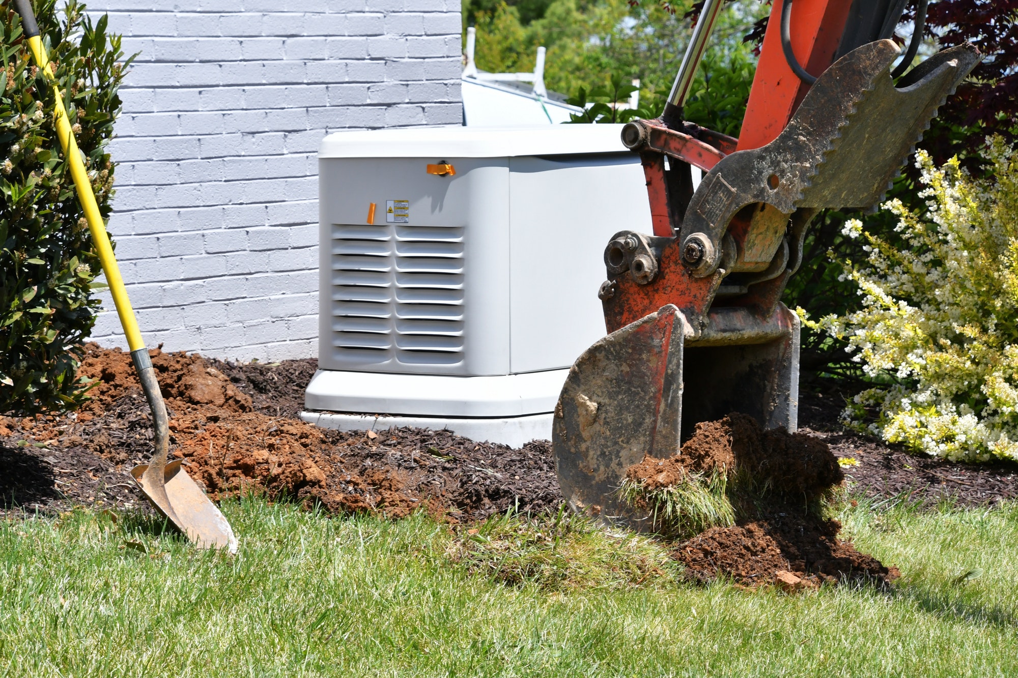 Backhoe digging dirt in lawn to install electrical & gas lines for house generator Scoopful soil sod